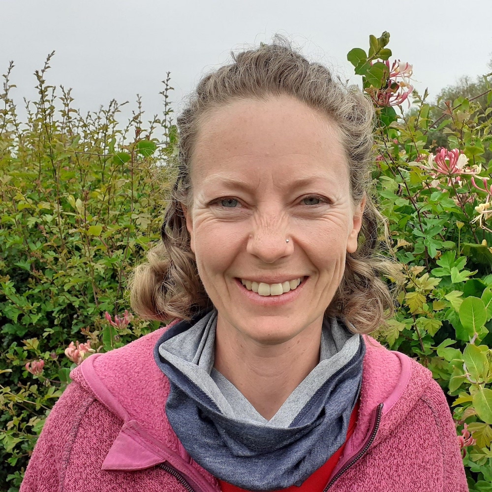 Photo of Catherine Cannon smiling in front of some foliage