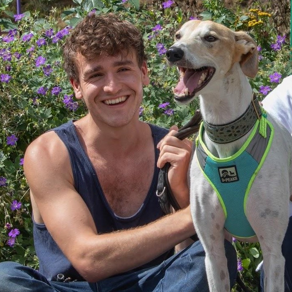 Photo of Robert Gordon smiling and kneeling next to a dog