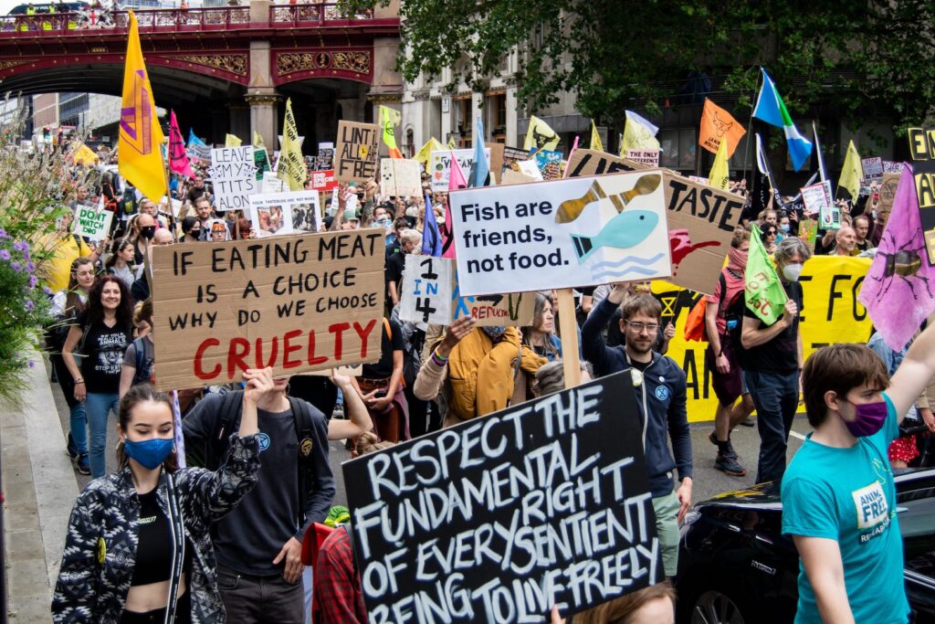 Photo of protesters walking down a street in Farringdon, London holding various colourful placards and flags
